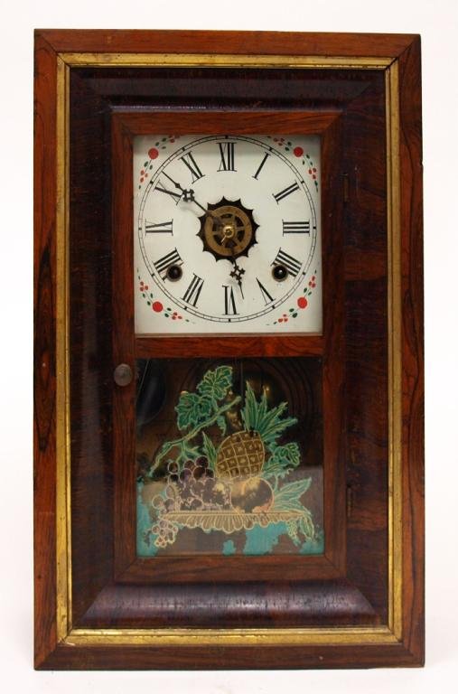 ANTIQUE AMERICAN WATERBURY OGEE WALL CLOCK: American Empire ogee Waterbury wall clock, 19th c., the wood case with gilt detail, Roman numeral face with painted embellishments, the glass door reverse painted in gilt fruit motif, retaining windin