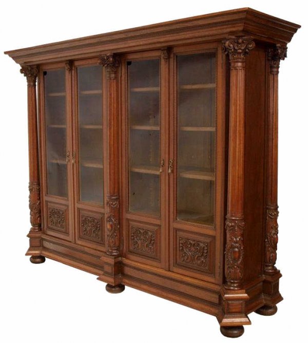 MAGNIFICENT SPAIN CARVED FOUR DOOR BOOKCASE: Northern Spain carved oak bookcase, c. 1890, the projecting cornice above dual bookcase sections, each having a pair of glazed doors flanked by Corinthian columns, foliated carving on lower panels, th