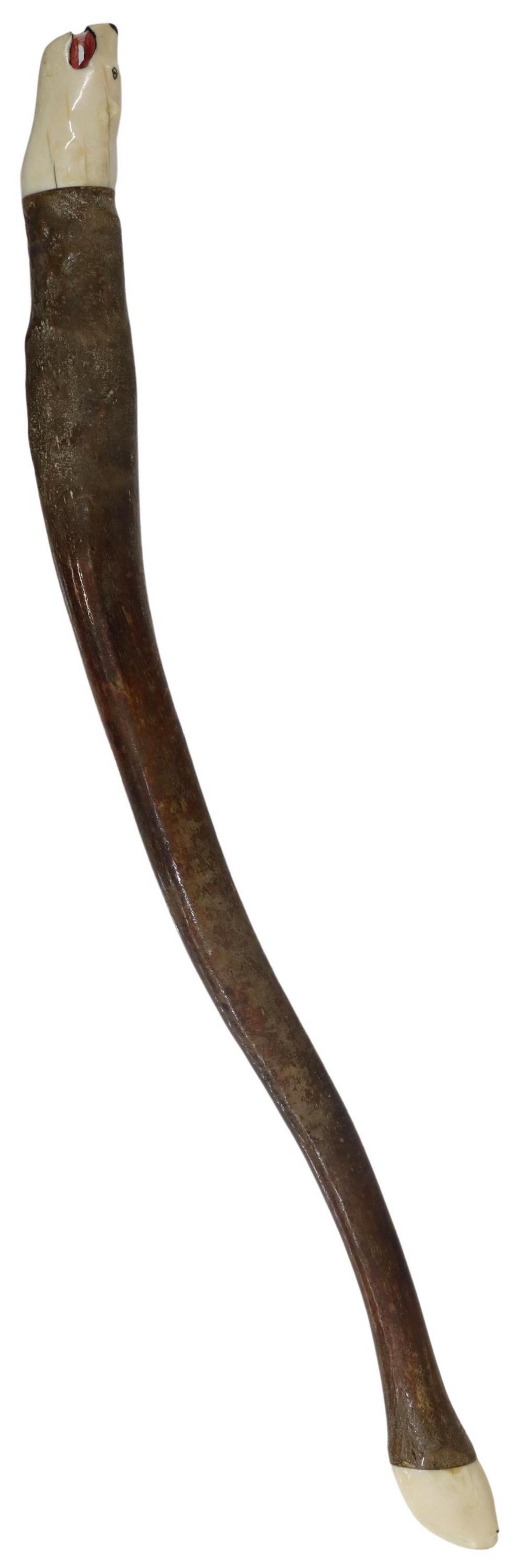 FOSSILIZED WALRUS OOSIK CARVED BEAR & WALRUS ENDS: Fossilized walrus baculum, a polished oosik or penile bone, with carved walrus tusk added at each end, one end depicting a polar bear head with open mouth baring teeth, the opposite end with a head of