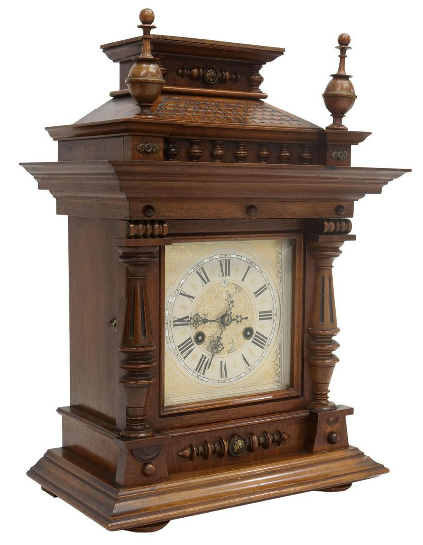 GERMAN JUNGHANS CARVED WALNUT MANTEL CLOCK: German chiming shelf clock, Junghans, late 19th/ early 20th c., having fancy architectural form carved walnut case, decorated with roof tiles, turned finials and fluted column supports, stepped base, 