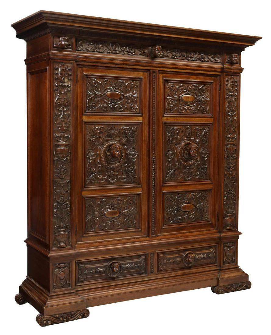 ITALIAN RENAISSANCE REVIVAL CARVED WALNUT ARMOIRE: Italian Renaissance Revival walnut armoire, Carlo Puccini, early 20th c., cornice with dentil molding, frieze with three projecting putti masks, scrolling foliage, two doors flanked by carved foliage 