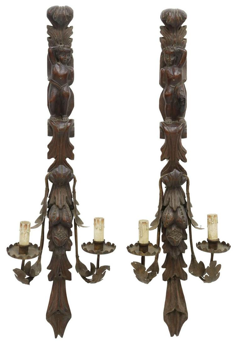 (2) ITALIAN FIGURAL CARVED TWO LIGHT WALL SCONCES: (pair) Italian walnut wall sconces, 19th c., carved backplate with putto, fruit pendants, issuing two wrought iron arms, each ending in bobeche and faux candle, in need of wiring, approx 32.5"h, 10.5"