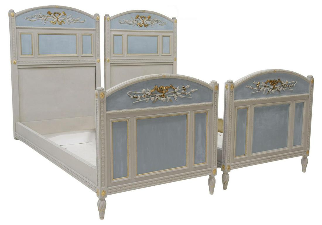 (2) LOUIS XVI STYLE PARCEL GILT & PAINTED BEDS: (lot of 2) Louis XVI style parcel gilt and painted beds, 19th c., crest with crossed torch and quiver of arrows, laurel leaf molding, paneled headboard and footboard, rising on tapered fluted legs wit
