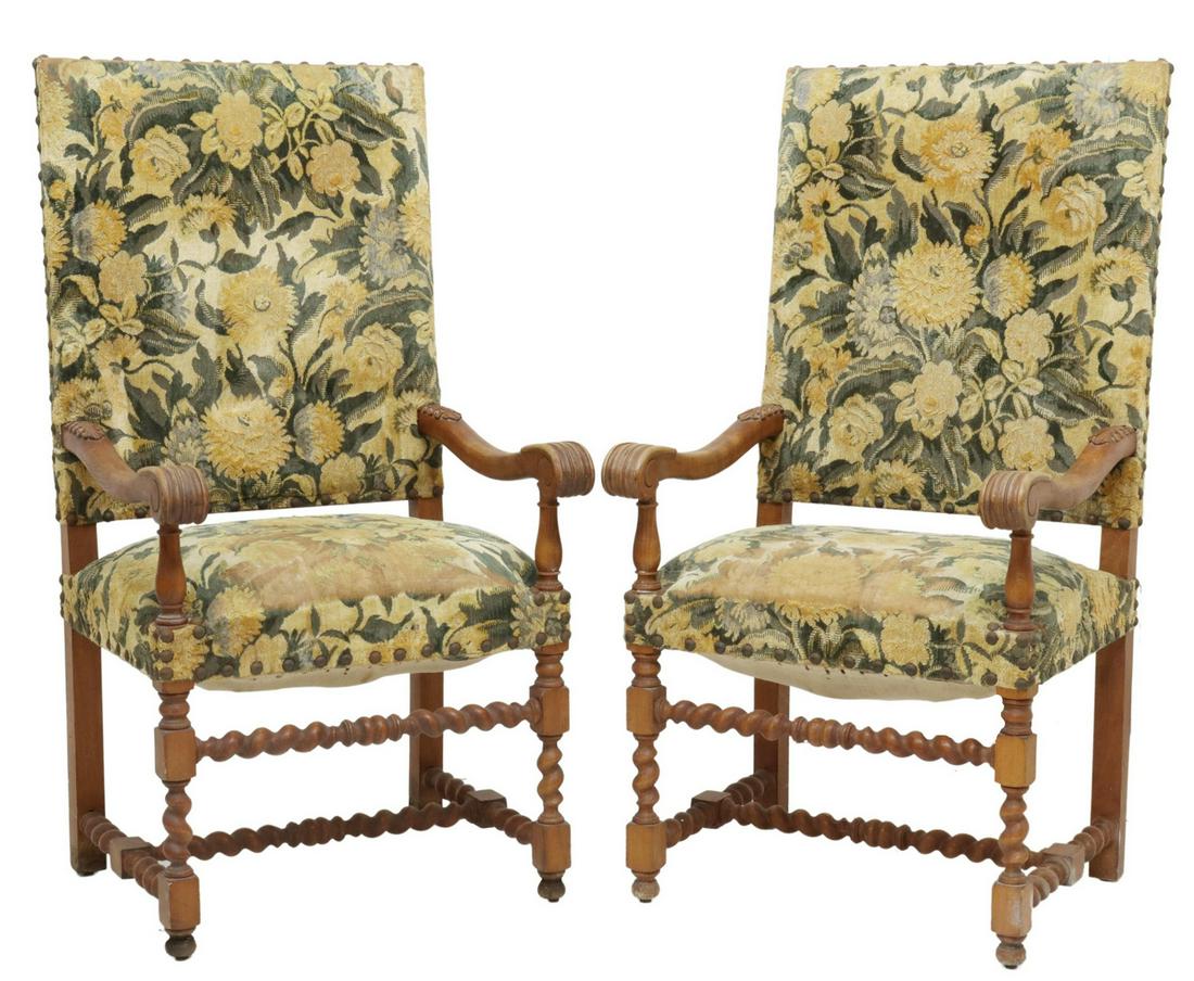 (2) FRENCH LOUIS XIII STYLE UPHOLSTERED FAUTEUILS: (pair) French Louis XIII style armchairs, early 20th c., upholstered back and seat, with large tack trim, carved arms with acanthus and scroll details, rising on spiral-turned legs, joined by H stretc
