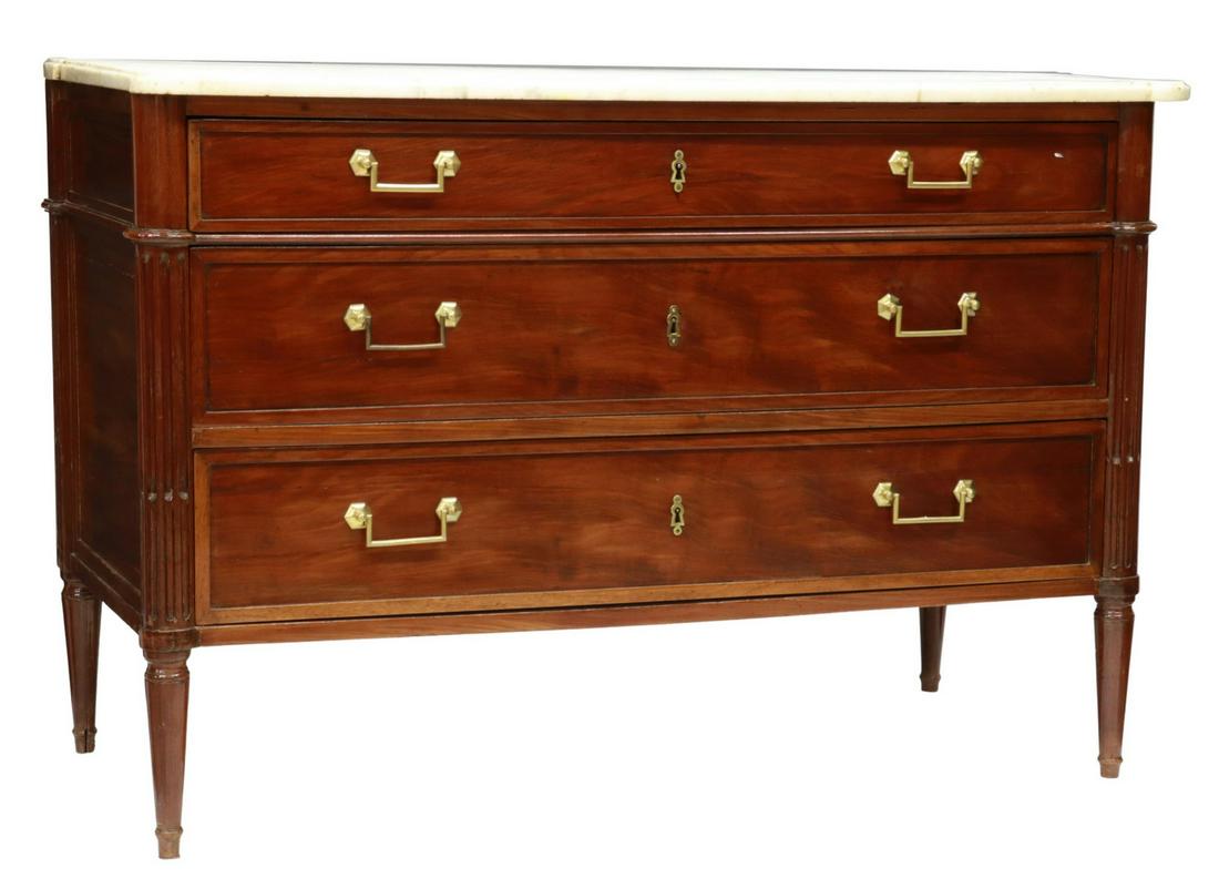 FRENCH LOUIS XVI STYLE MARBLE-TOP MAHOGANY COMMODE: French Louis XVI style mahogany commode, early 20th c., shaped marble top with cup corners, three drawers flanked by fluted corner posts, rising on tapered legs, separation at side panels, approx 34.7