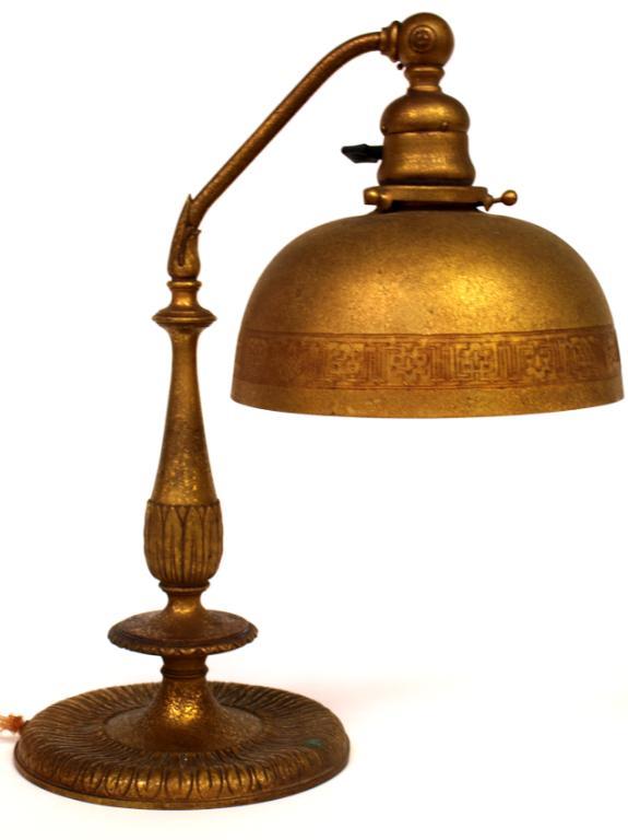 TIFFANY STUDIOS GILT & ETCHED METAL DESK LAMP: Tiffany Studios gilt bronze and etched metal desk lamp, a curved arm with adjustable end holding domical shade, foliate motif on standard and wide pedestal foot, marked "Tiffany Studios New York", 639