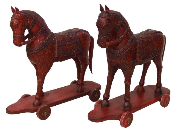 (PAIR) ANTIQUE CARVED WOOD TEMPLE HORSES, 19th C.: (pair) Antique carved wood Buddhist temple horses, Northwest India, 19th c., each with elaborate decoration and placed in a standing position on a platform with four wood wheels, 35"h, 35"w, 12"d