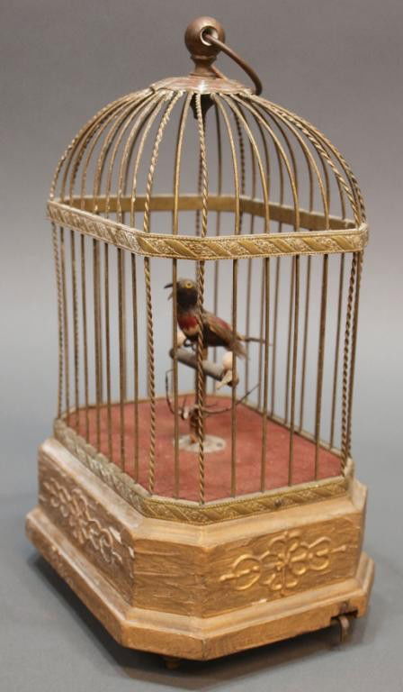 ANTIQUE GERMAN SINGING BIRD CAGE AUTOMATON: German singing bird automaton, early 20th c., a single bird perched on a stand, within a metal cage mounted on a gilded wooden base decorated in a floral motif, raised on four short feet, wind-up mech