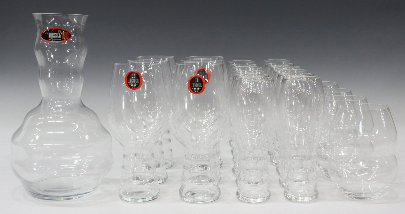 (23) RIEDEL COLORLESS GLASS WINE STEMS & DECANTER: (lot of 23) Riedel colorless glass stemware and decanter, all having acid-etched mark underfoot, including: (12) 'O' champagne glasses, approx 6.5"h, 2"diam; (6) 'O' red/ white taster glasses, approx 