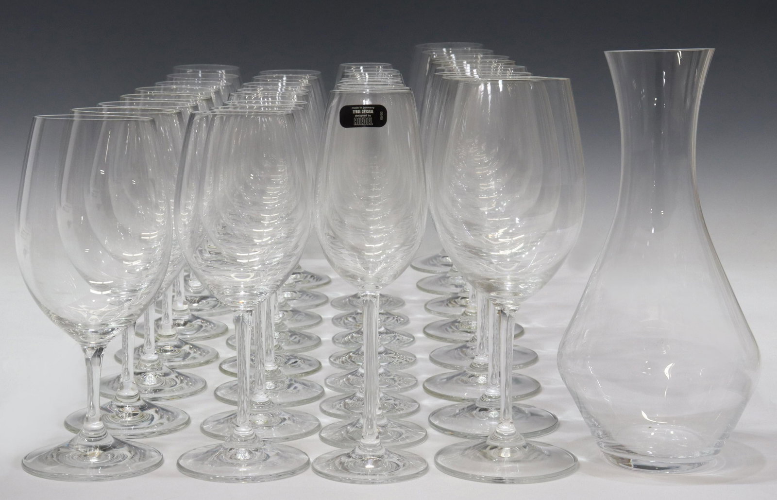 RIEDEL COLORLESS GLASS WINE STEMS & DECANTER: (33) Riedel colorless glass stemware and decanter, all having acid-etched mark underfoot, including: (8) champagne flutes, approx 8.5"h, 2"diam; (8) Cabernet/ Merlot stems, approx 9"h, 2.75"diam; (8) 