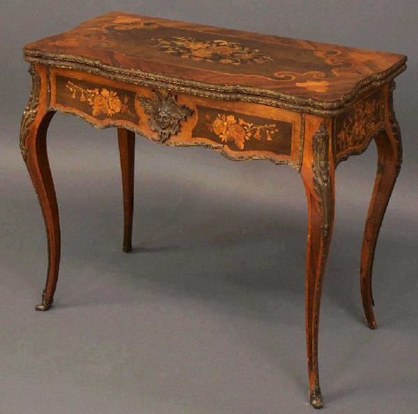 19TH C FRENCH LOUIS XV STYLE MARQUETRY GAMES TABLE: French Louis XV style marquetry games table, 19th c., the flip top finely inlaid with floral reserves, foliate gilt metal trim and figural mask on the apron further inlaid in a floral motif, the top o