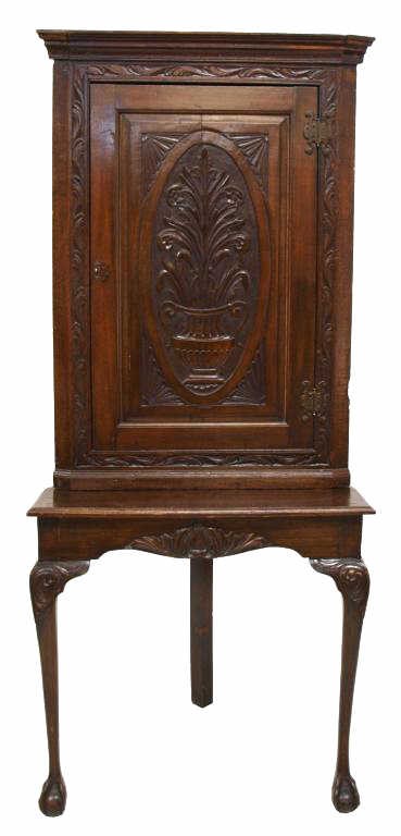 CARVED ENGLISH 19TH C. CORNER CUPBOARD ON STAND: English Victorian hanging corner cupboard on stand, c. 1880, a stepped cornice over a single door with vase and floral carving, three interior shelves, set on a later corner table with tapered circula