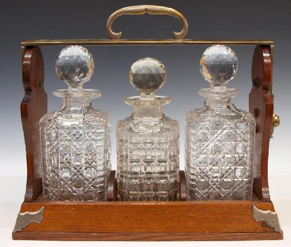 MAPPIN & WEBB OAK & GILT BRASS TANTALUS SET: Mappin & Webb, English oak brass bound tantalus, "Mappin & Webb facing the Mansion House London", lockable swiveling carrying handle marked with a crown over 'Tantalus' on one side, the other Betjeman