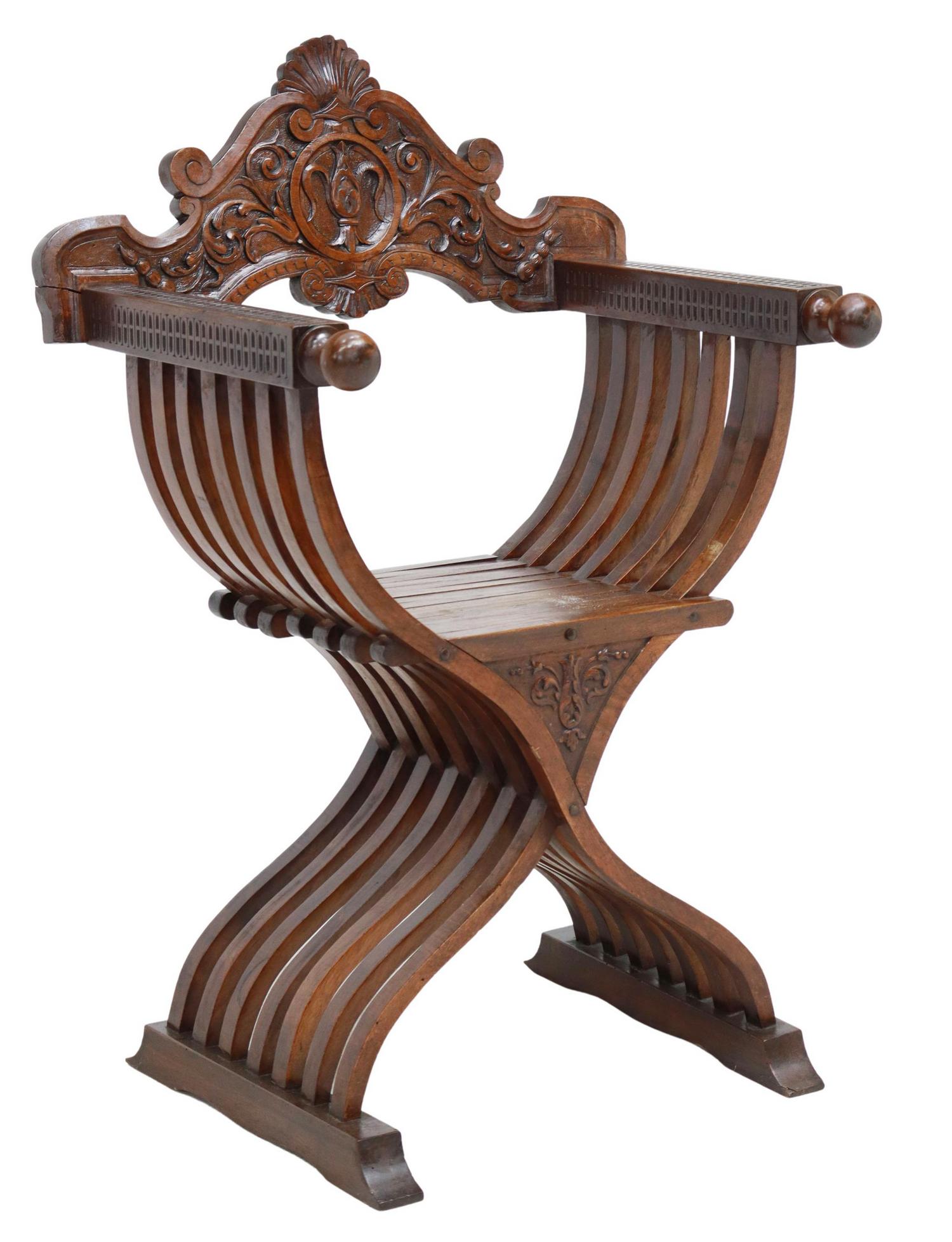 ITALIAN CARVED WALNUT SAVONAROLA CHAIR: Italian walnut Savonarola chair, 20th c., carved backrest, over squared arms ending in turned handholds, folding slatted curule frame, molded shoe base, approx 41"h, 28"w, 21.5"d Start Price: $80.00