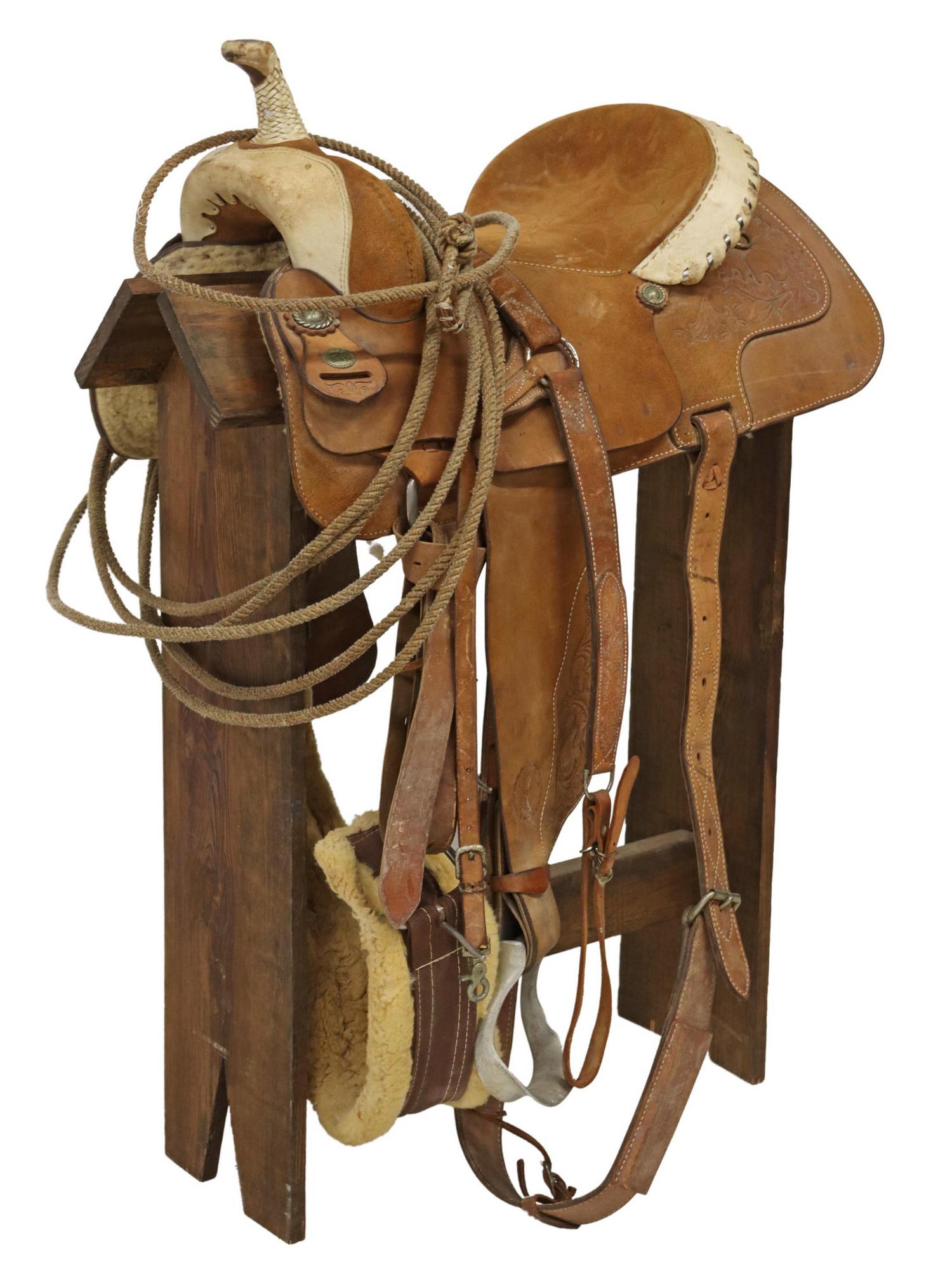 WESTERN CIRCLE Y TEXAS SUEDE SADDLE ON STAND: Western suede saddle, Circle Y, Yoakum, Texas, 14.5" seat, contrasting light brown and white foliate tooled leather, with patinated metal conchos, accompanied by wooden stand Start Price: $150.00