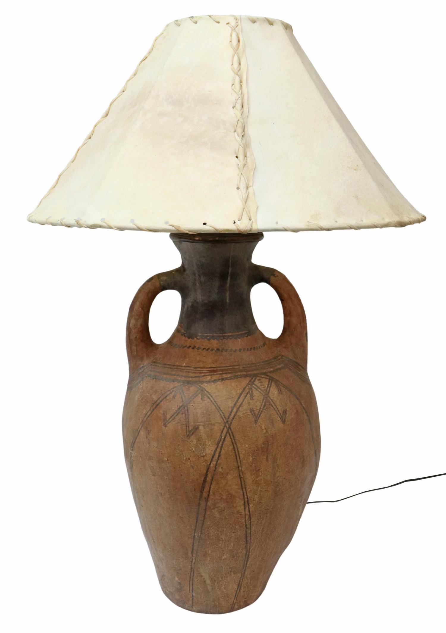 BERBER POTTERY JUG TABLE LAMP WITH RAWHIDE SHADE: Large Moroccan Berber pottery water jug, now fashioned as a table lamp, having laced rawhide shade, over two-handled painted earthenware jug, approx 38"h, 24.25"diam, 23.5lbs Start Price: $100.00