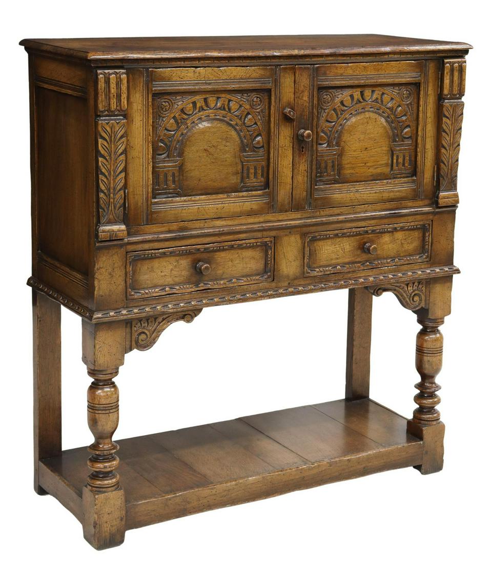 ENGLISH JACOBEAN STYLE OAK WINE CABINET ON STAND: English Jacobean style oak wine cabinet, attributed to Titchmarsh & Goodwin, 20th c., two doors with arcaded panels, over two drawers, rising on turned front legs, joined by platform base, apparently 