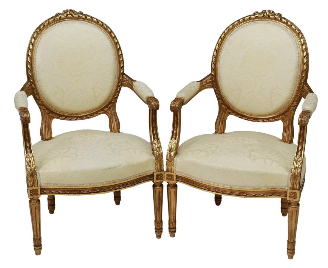 (2) LOUIS XVI STYLE GILTWOOD OVAL BACK FAUTEUILS: (pair) French Louis XVI style giltwood armchairs, early 20th c., floral crest, medallion back with ribbon twist molding, padded arms ending in acanthus scroll handholds, upholstered seat, rising on ta