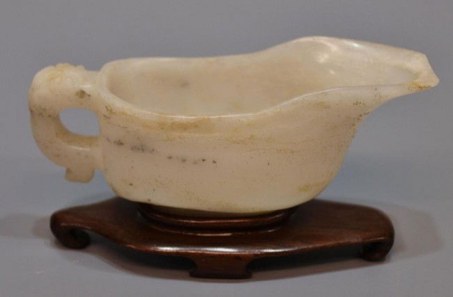 19TH C. CHINESE MILK WHITE JADE HANDLED CUP: Diminutive Chinese white jade cup, 19th c./possibly earlier, the rounded cup with elongated spout, the handle in the form of a Chi Long climbing over the rim, the stone is translucent milk white jade,