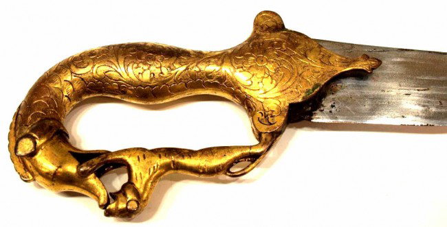 SCARCE & EXCEPTIONAL INDO-PERSIAN GILDED SWORD: Exceptional Indo-Persian sword, early 19th c., the gilded hilt in the form of a makar (mythical beast) with intricate floral and foliate engraving, holding a tiger which forms the knuckle guard, the b