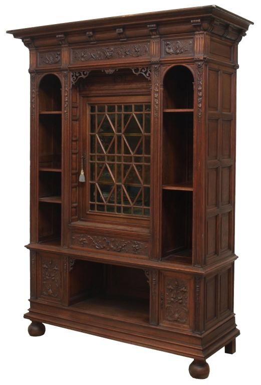 FINE FRENCH CARVED OAK GLAZED DOOR BOOKCASE: French Renaissance style carved oak cabinet, 19th c., the overhang cornice surmounting the case with slim open display shelves on either side, central mullioned door situated above a drawer and cabine