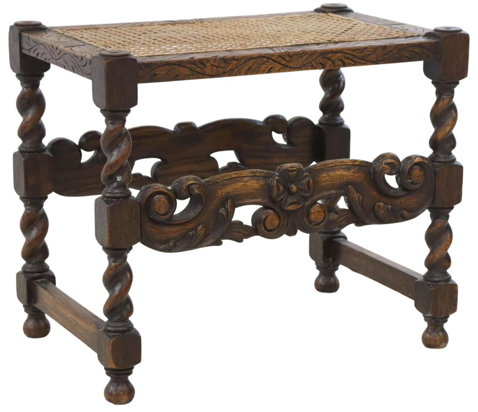 JACOBEAN STYLE CANE SEAT CARVED OAK BENCH: Jacobean style carved oak bench, 20th c., inset cane seat, surrounded by carved foliate border, over scrolled apron, rising on turned and stretcher-joined legs, ending in bun feet, approx 18.5"h, 21.7