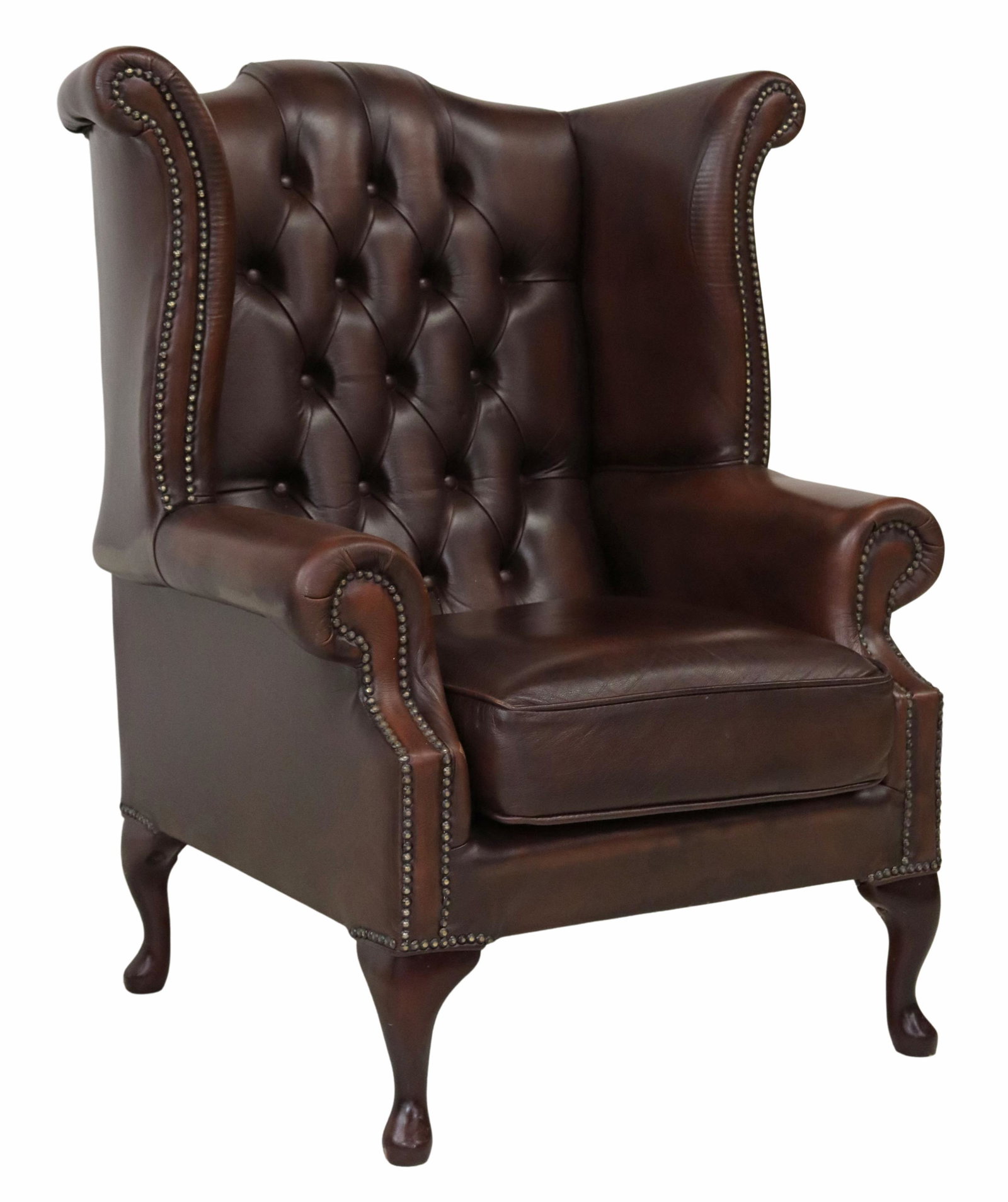 QUEEN ANNE STYLE LEATHER WINGBACK ARMCHAIR: Queen Anne style wingback armchair, late 20th c., in brown leather upholstery, with button-tufted back, rolled arms, loose seat cushion, nail head trim, rising on cabriole legs, ending in pad feet, re