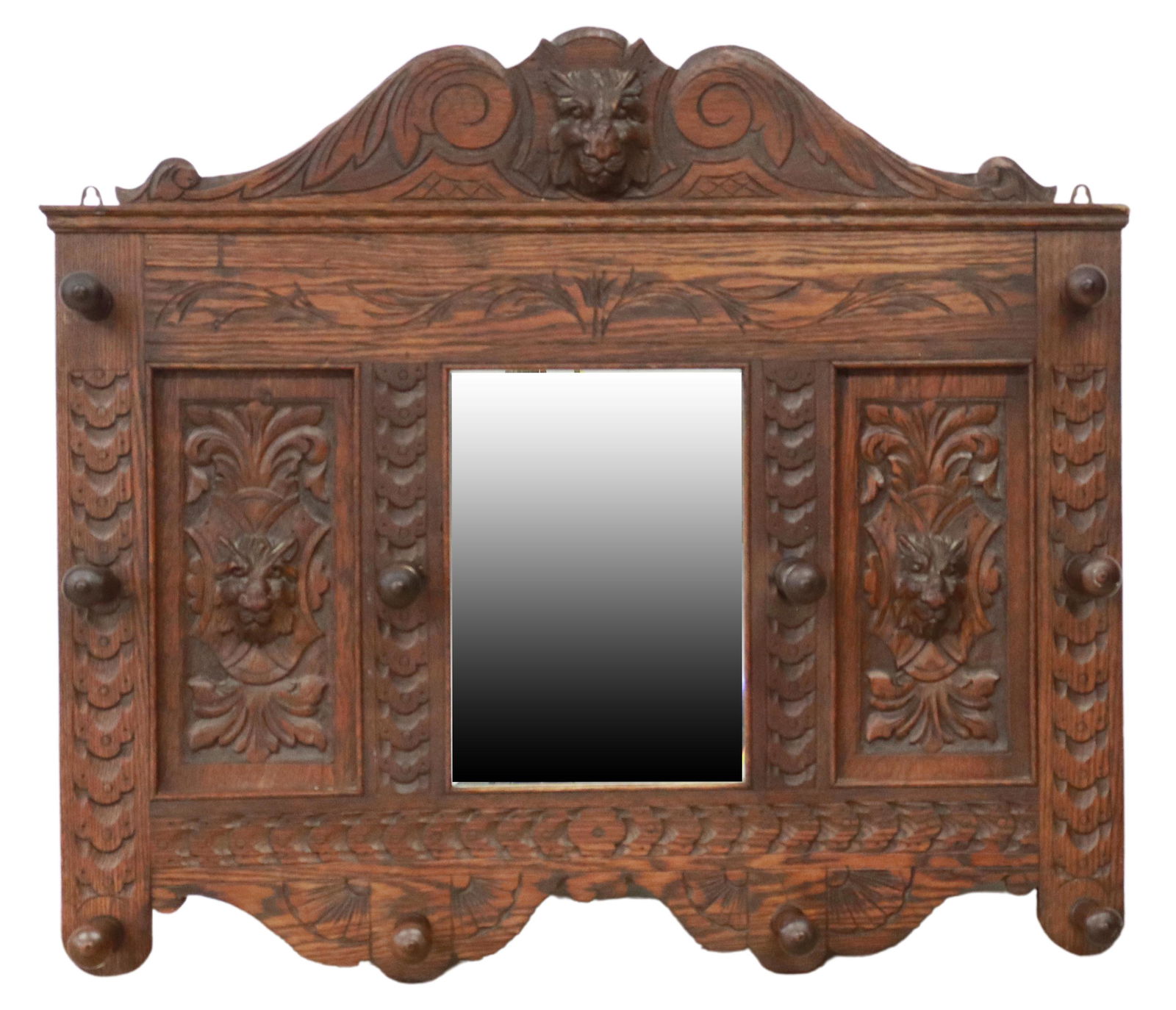 ENGLISH CARVED OAK MIRRORED WALL HAT RACK: English carved oak mirrored wall mounted hat/ coat rack, 19th c., carved lion mask crest, over shaped scrolling frame, issuing ten turned hooks, lion mask panels, centering beveled mirror plate, appro