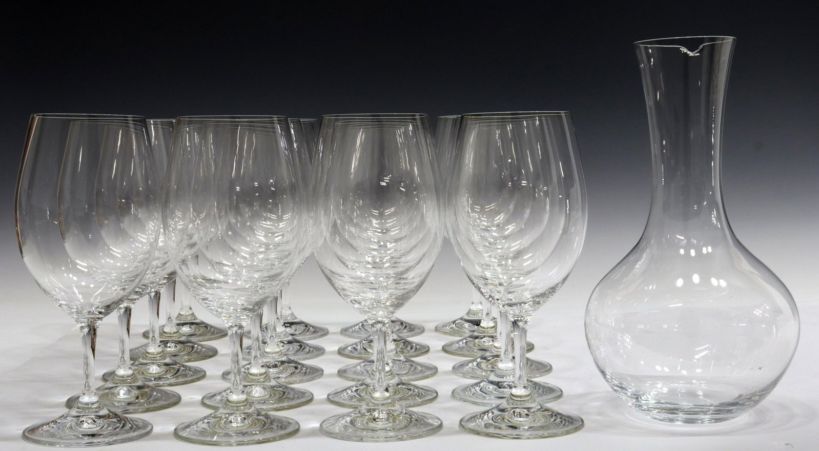 (21) RIEDEL COLORLESS GLASS STEMWARE & DECANTER: (lot of 21) Riedel colorless glass drinkware, all having acid-etched mark underfoot, comprising: (20) red wine stems, approx 8"h, 3.5"diam; (1) decanter, approx 9.75"h; 7.3lbs total Start Price: $100.