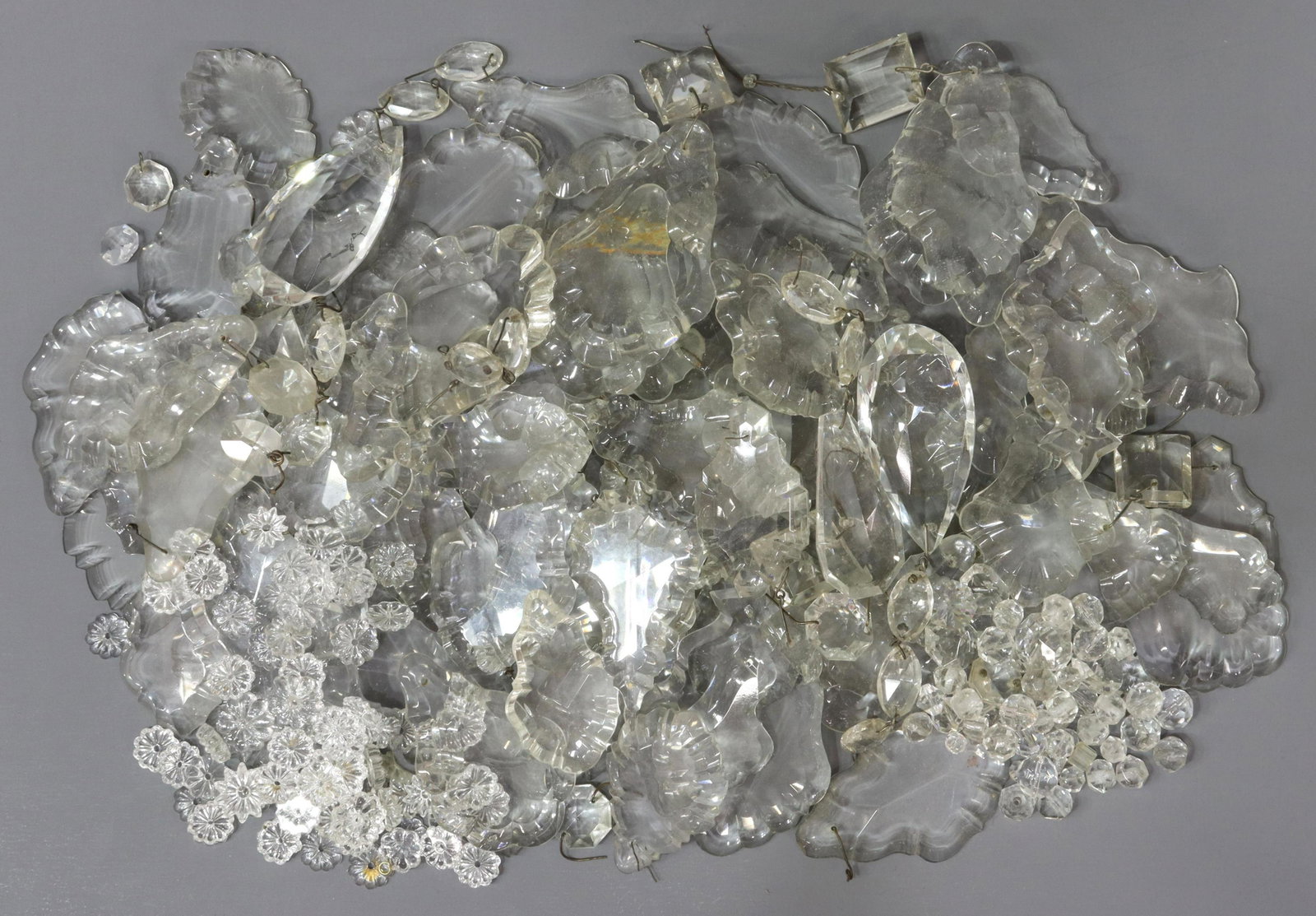 (LOT) CHANDELIER PARTS CRYSTAL PRISMS, PENDALOGUES: (lot) Collection of crystal chandelier parts, many French and flat pendalogues/ prisms, glass rosettes, beads, some chips, largest: approx 4"l, 2.75"w, 6.5lbs total Start Price: $100.00