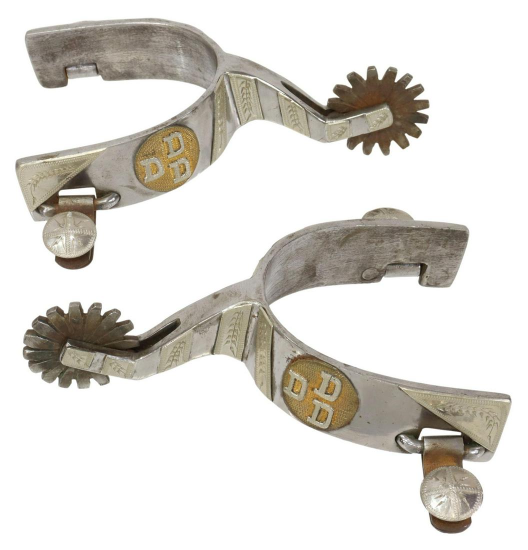 WESTERN NICKEL-PLATED FOLIATE COWBOY SPURS: (pair) Western nickel-plated spurs, with engraved foliate accents throughout, gold-tone medallion at sides bearing "DDD," stamped "DEE 189" at heel, 16 point 1.5" diameter rowels, inside yoke: 3.5"h, 