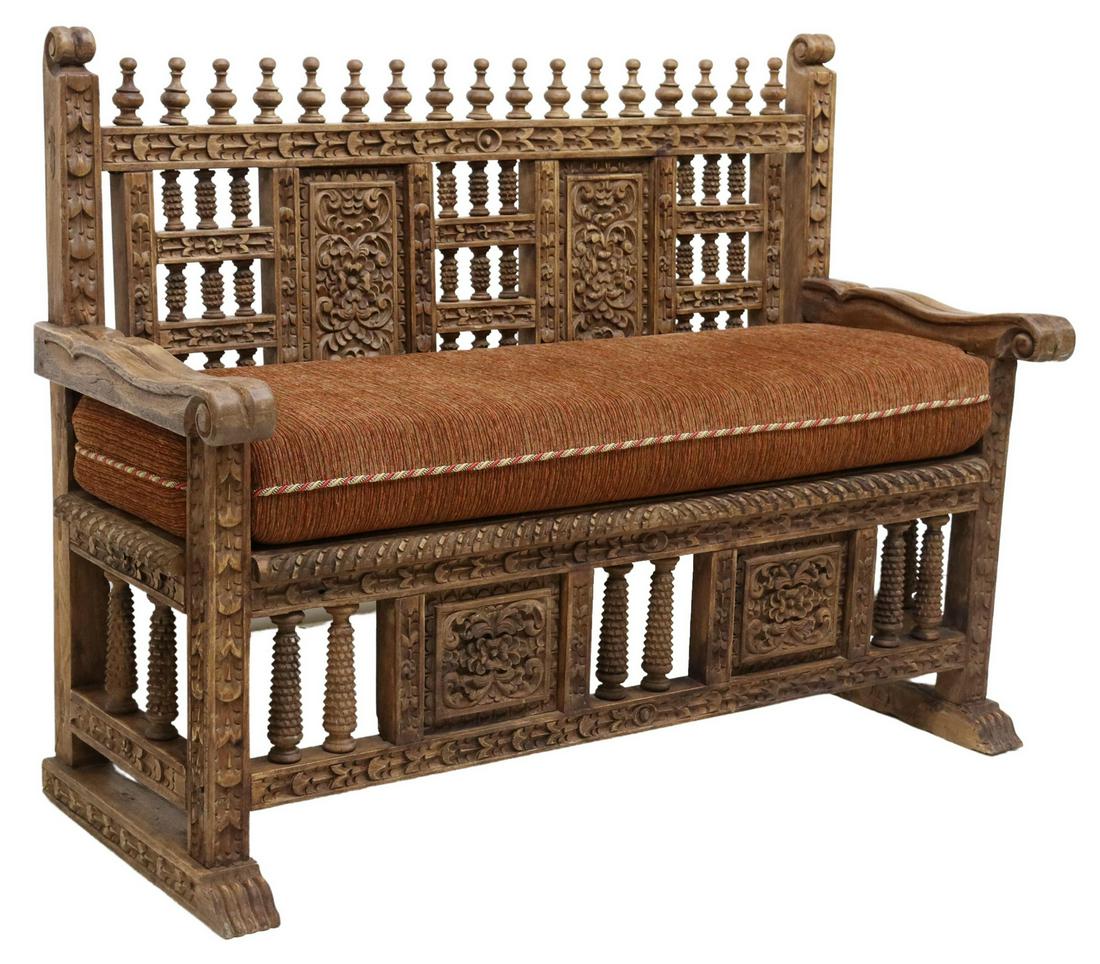 PERUVIAN COLONIAL STYLE HAND-CARVED WOOD BENCH: Peruvian Colonial style highback bench, 20th c., top rail surmounted by turned finials, carved and spindled back, loose seat cushion, scrolled arms, rising on carved shoe feet, approx 42.5"h, 55.75"w,