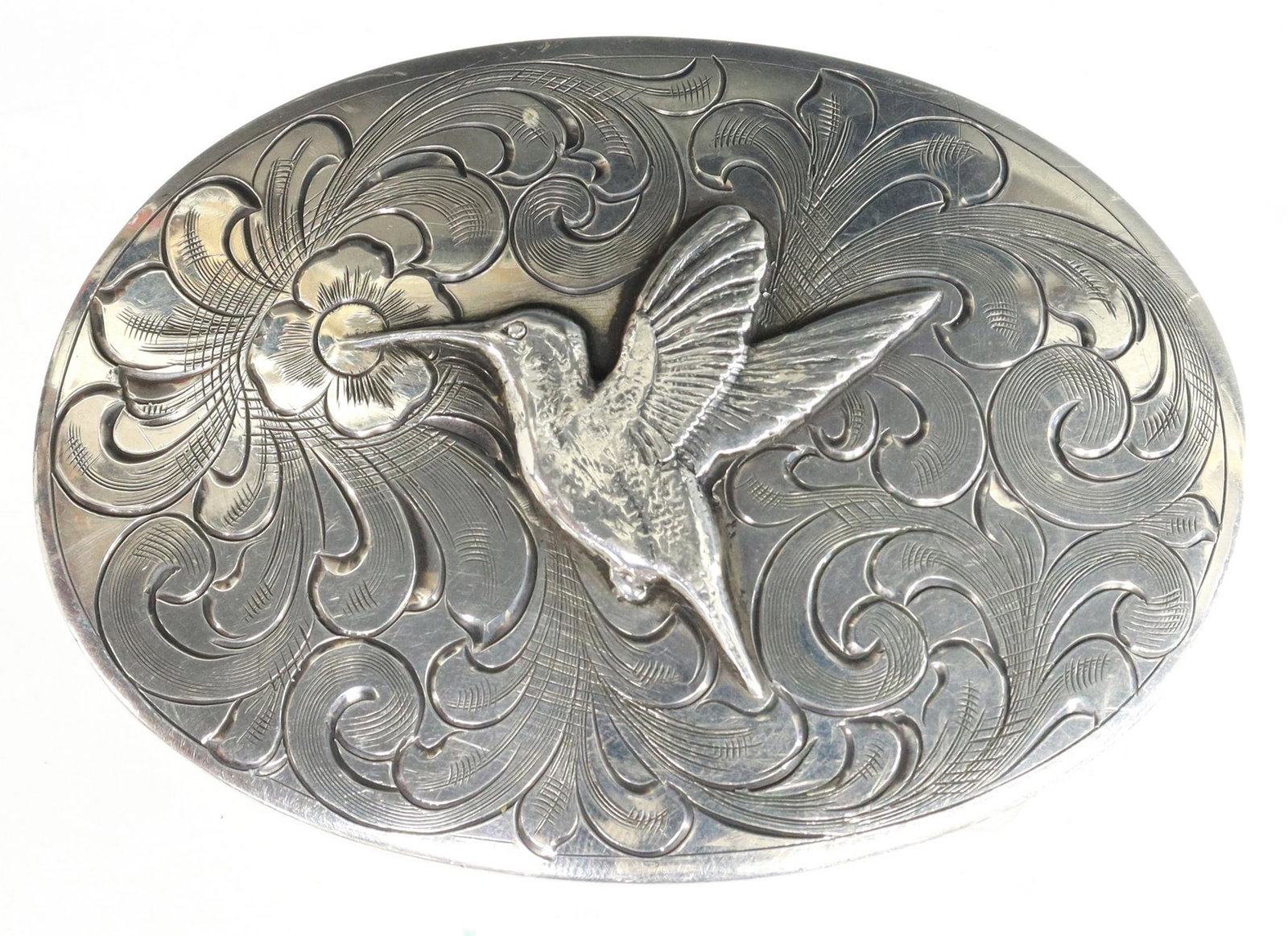 CLINT ORMS TEXAS SILVER HUMMINGBIRD BELT BUCKLE: Silver (content unknown) belt buckle, Clint Orms Engravers & Silversmiths, Texas, oval form with foliate and floral motif, centering a hummingbird, buckle: approx 0.75"l, 2.5"w, accommodating: approx 