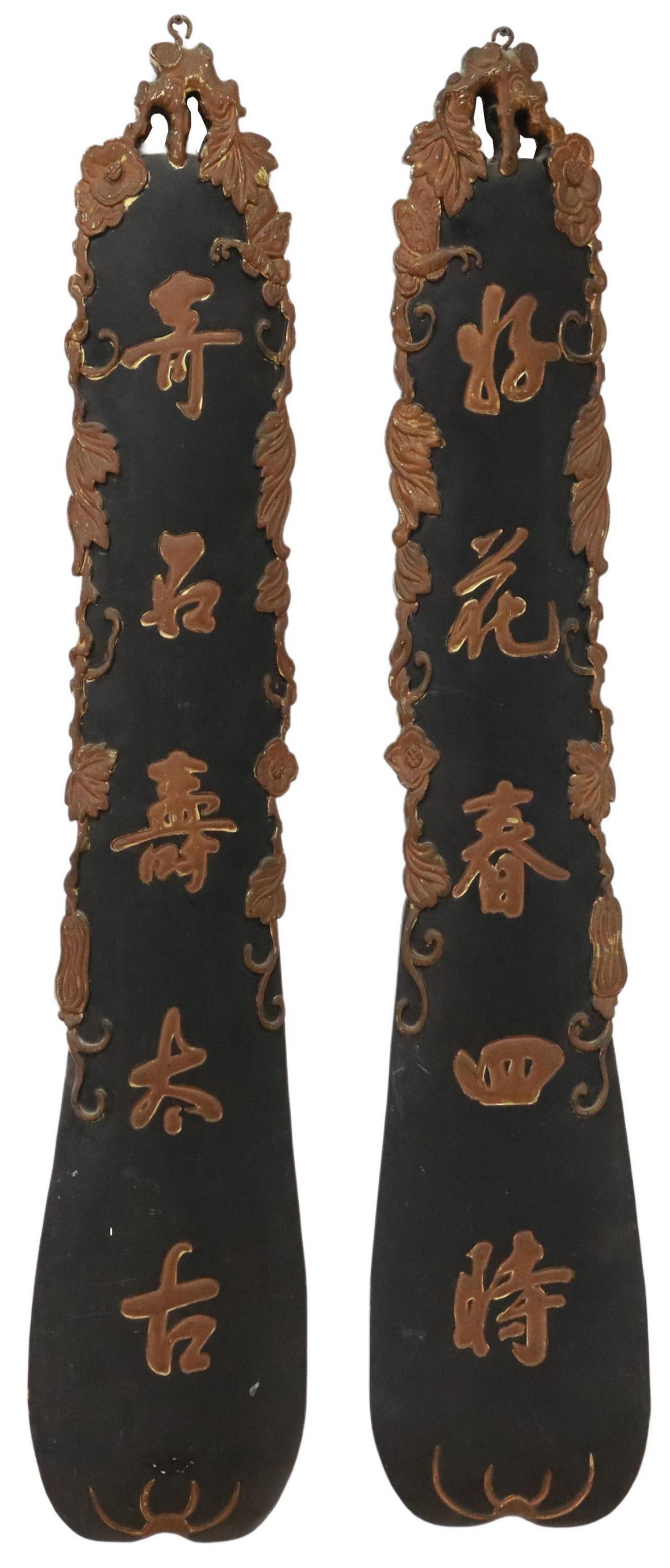 (2) CHINESE ARCHITECTURAL HANGING WALL PANELS: (lot of 2) Chinese wood architectural hanging wall panels, 20th c., each in black and brown painted wood, with faint gilt accents to carved elements, featuring central characters and flanking foliate 