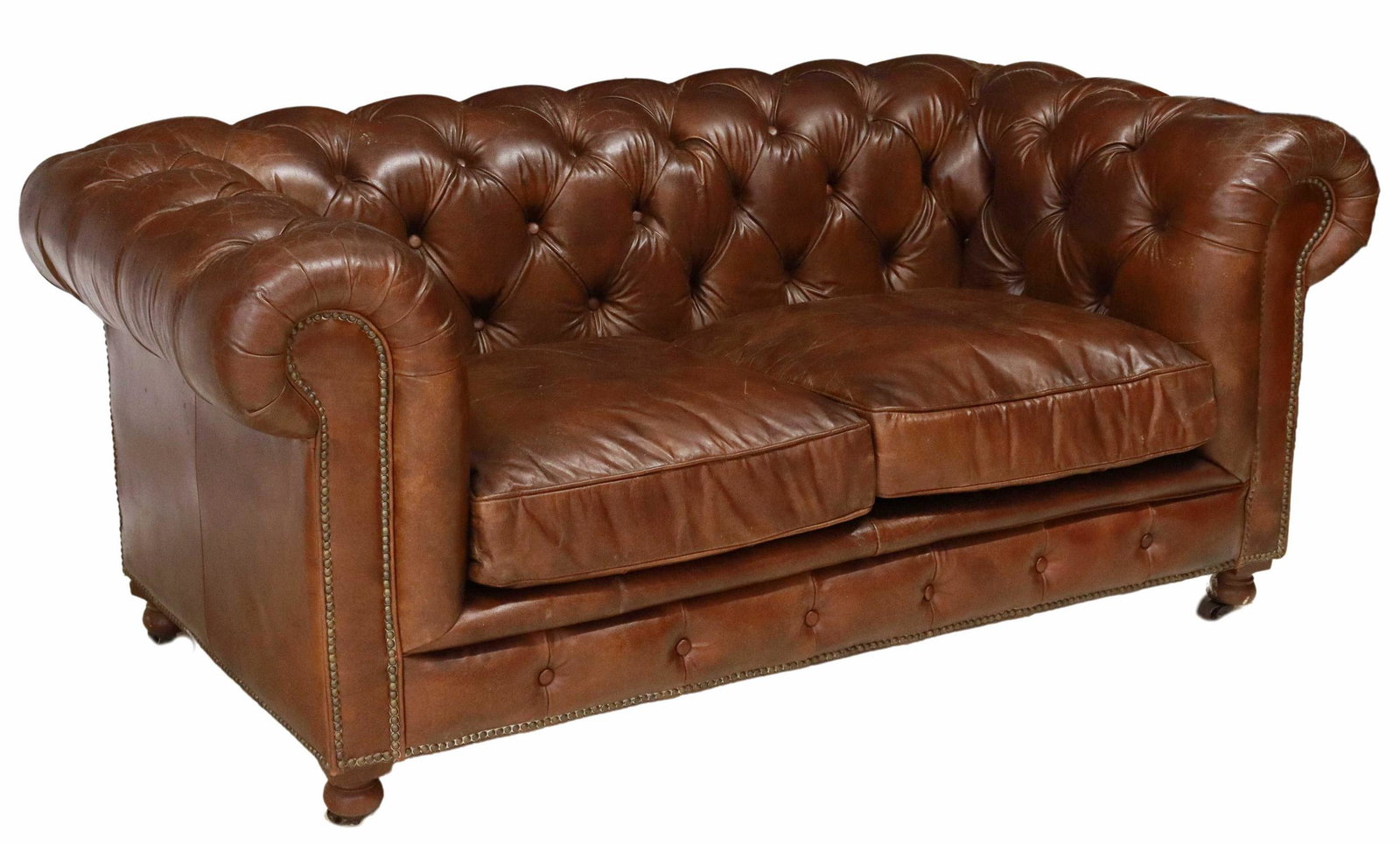 BROWN LEATHER CHESTERFIELD TWO-SEAT SOFA: Chesterfield two-seat sofa, 20th c., brown leather upholstery, button-tufted rolled back and arms, brass tack trim, two loose seat cushions, bun feet on casters, approx 31.5"h, 70"l, 38"w, seat height