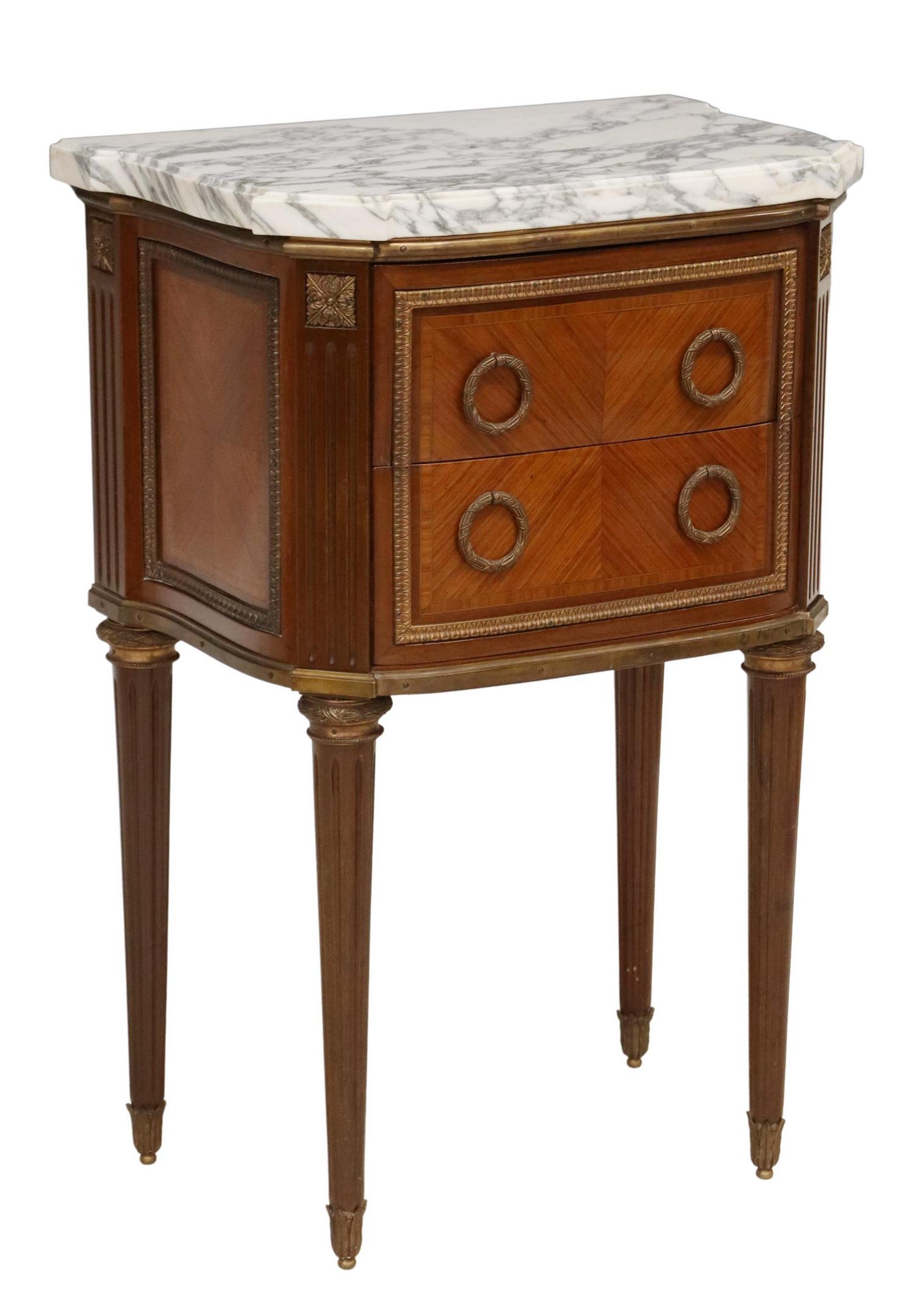FRENCH LOUIS XVI STYLE MARBLE-TOP NIGHTSTAND: French Louis XVI style mahogany bedside cabinet, early 20th c., having marble top, over two drawers, with gilt-metal laurel wreath pulls, rising on fluted and tapered legs, ending in foliate caps, app
