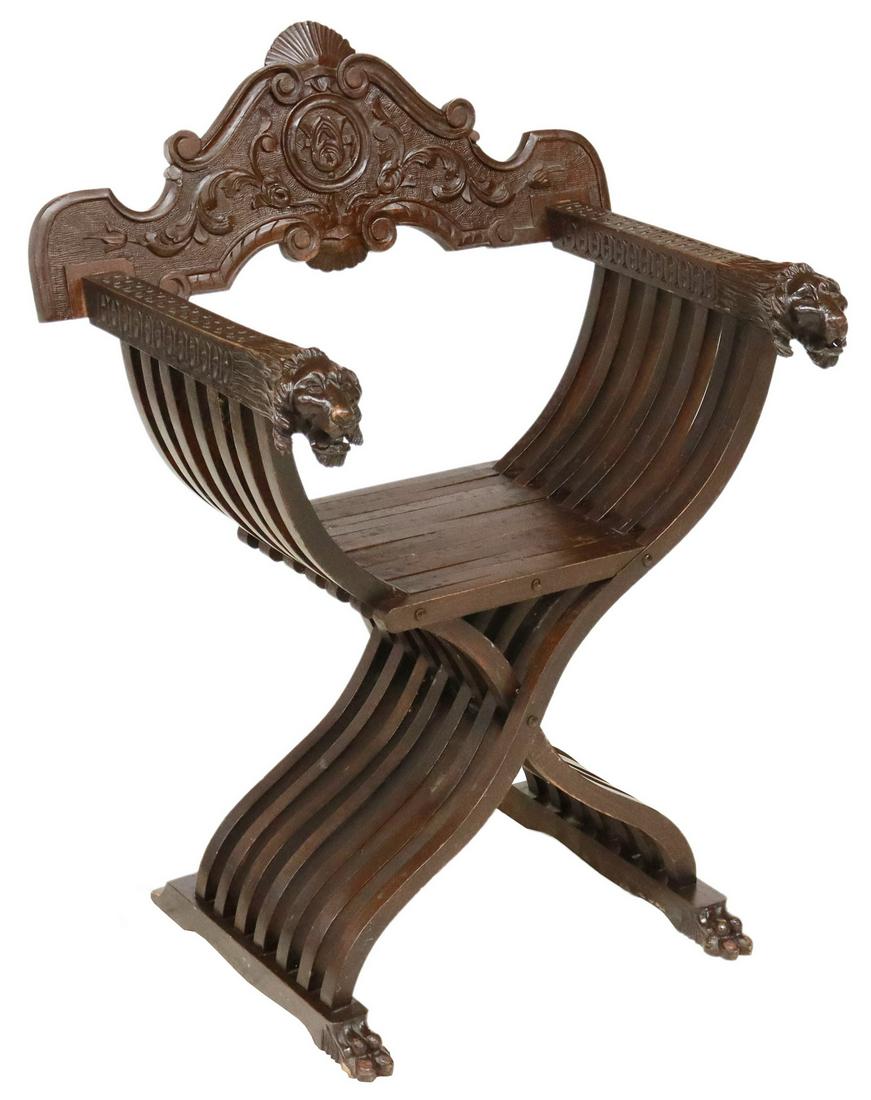 ITALIAN CARVED WALNUT SAVONAROLA CHAIR: Italian carved walnut Savonarola chair, early 20th c., carved back with shell crest and scrolling foliates, arms ending in lion head handholds, slatted curule frame, ending in paw feet, approx 37"h, 2