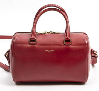 YVES SAINT LAURENT "BABY CLASSIC" LEATHER DUFFLE: Yves Saint Laurent "Baby Classic" duffle bag, in red leather, with gold-tone hardware, dual rolled top handles, optional flat adjustable shoulder strap, foil-stamped logo accent at front face, five