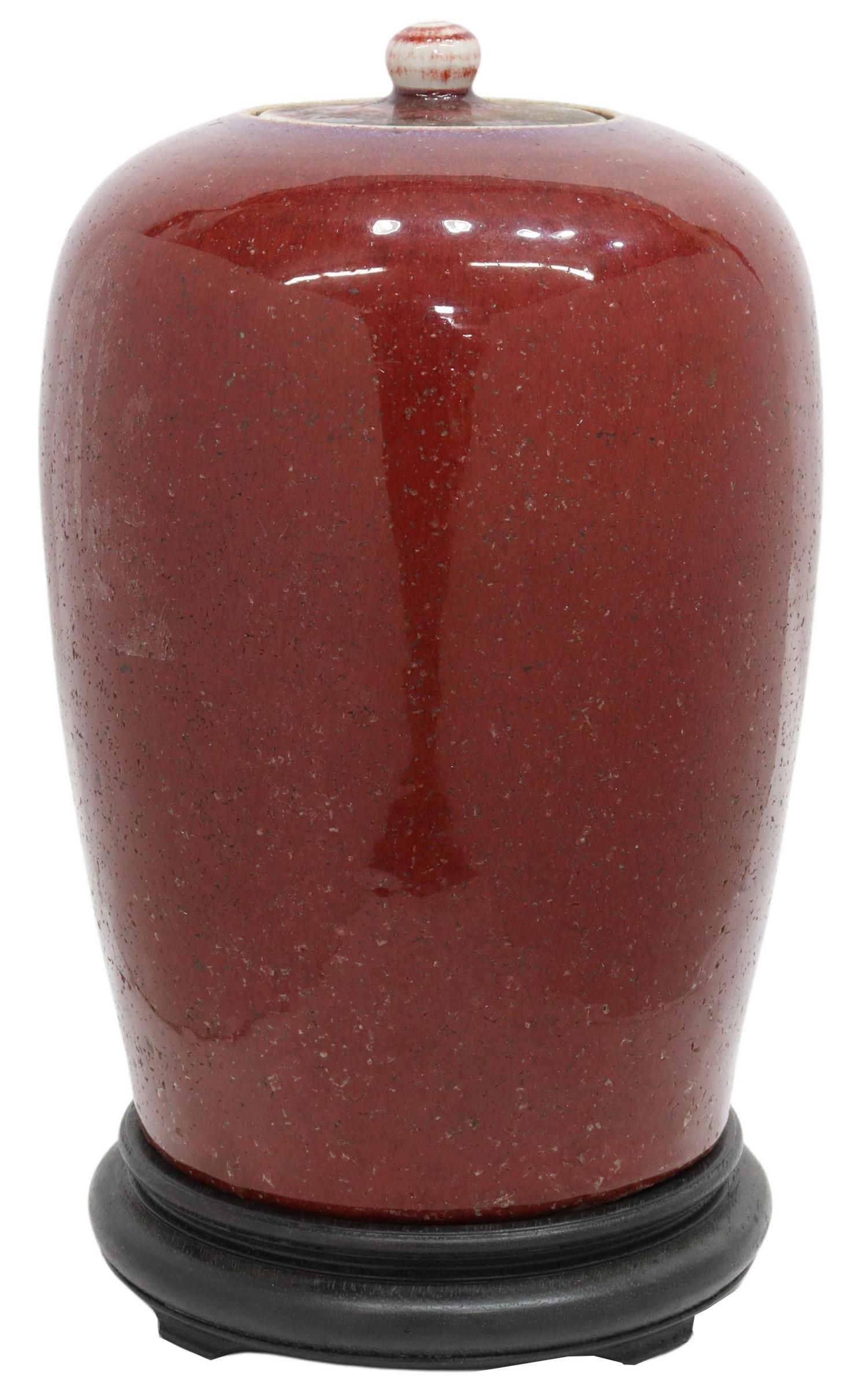 CHINESE SANG DE BOEUF PORCELAIN LIDDED JAR: Chinese sang de boeuf (oxblood) glazed porcelain lidded jar, rising on wood stand, approx 13.75"h, vase only: 13"h, 7.5"diam, 8.75lbs total Start Price: $125.00