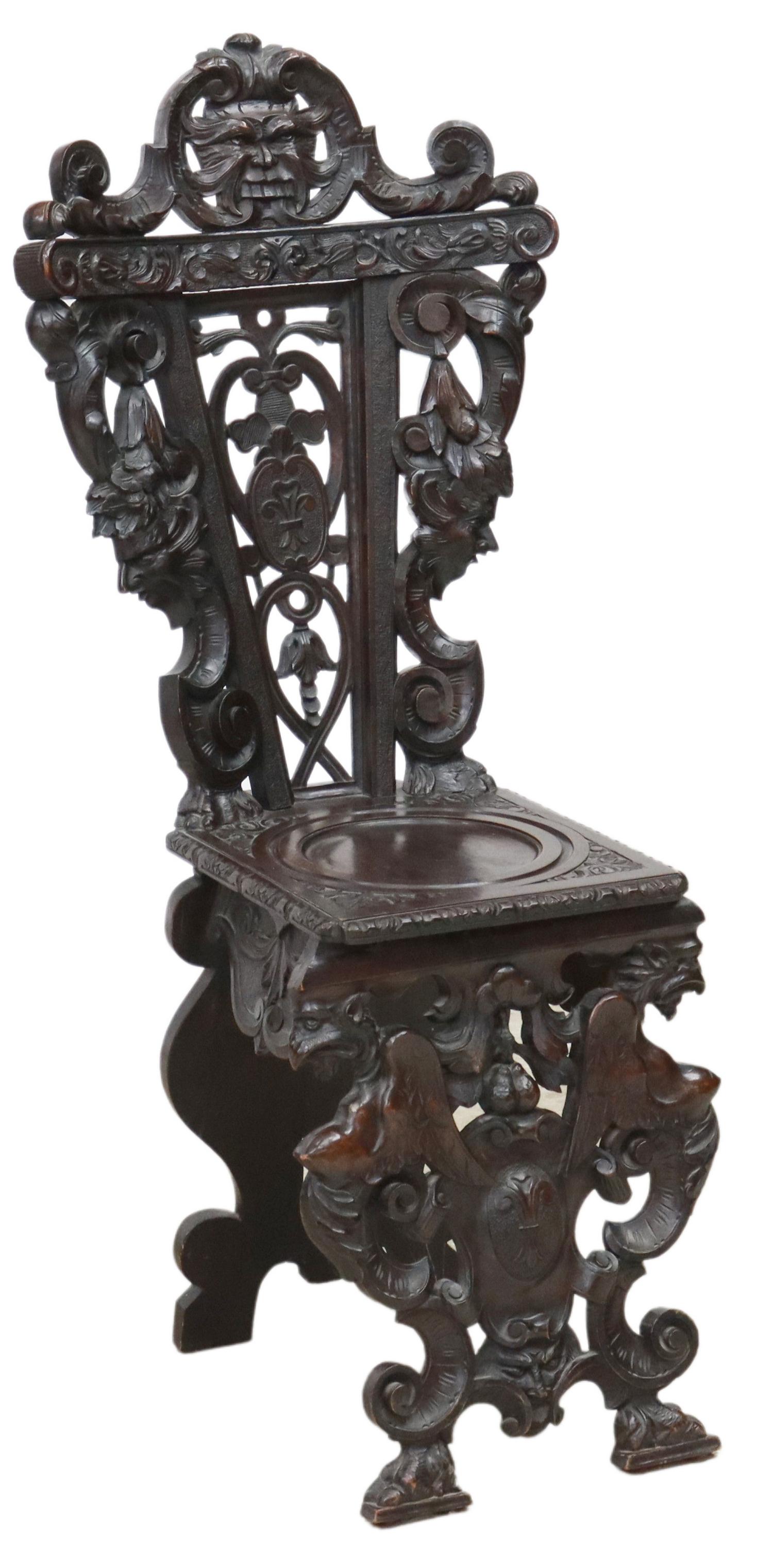 RENAISSANCE REVIVAL CARVED HALL CHAIR: Renaissance Revival heavily carved hall chair, early 20th c., carved grotesque crest, over openwork back, flanked by protruding masks, rising on double winged dragon supports, ending on paw feet, rest