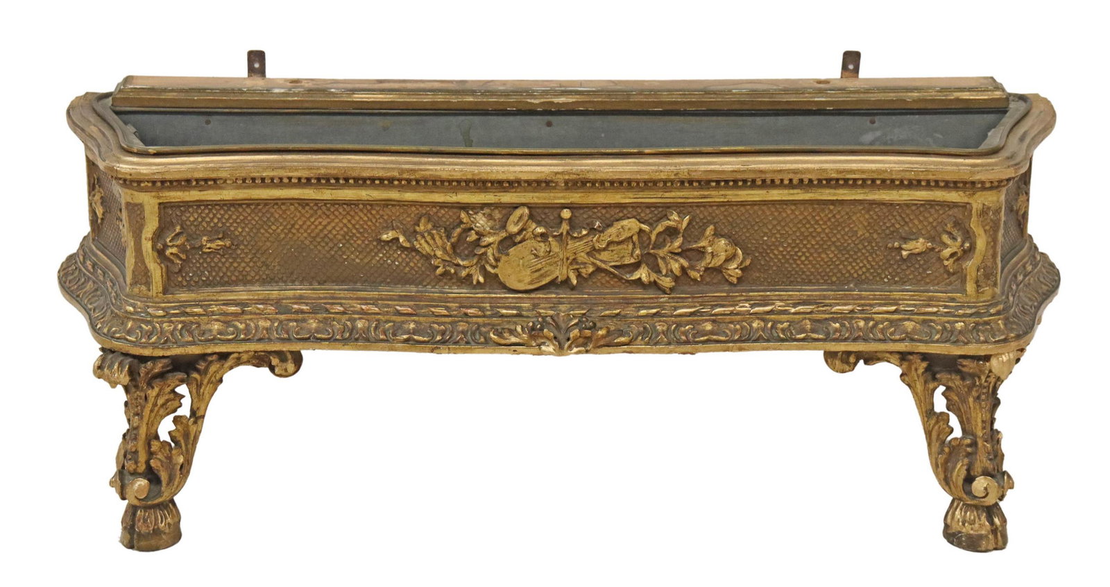 REGENCE STYLE GILTWOOD JARDINIERE: Regence style giltwood jardiniere, 19th c., shaped frame, with applied musical instrument motifs, rising on acanthus legs, ending in hoof feet, retaining metal liner, approx 17.75"h, 42"w, 12"d Start 