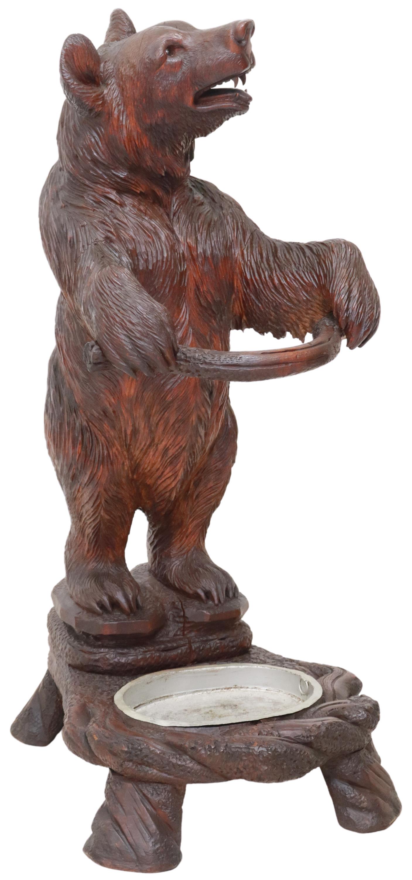 BLACK FOREST CARVED WOOD BEAR UMBRELLA STAND: Black Forest carved wood umbrella stand, early 20th c., modeled as a bear, with inset glass eyes, on integral plinth base, with metal drip tray, approx 36"h, 16"w, 19"d Start Price: $500.00