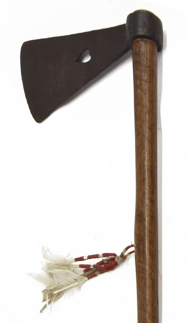 REPLICA NATIVE AMERICAN PLAINS-STYLE TOMAHAWK: Replica Plains-style tomahawk, contemporary, hand-forged with heart cutout, iron blade approx 8" x 4.25", mounted on a 32.5" shaft with beads, hide and feathers, 1.5lbs Start Price: $50.00