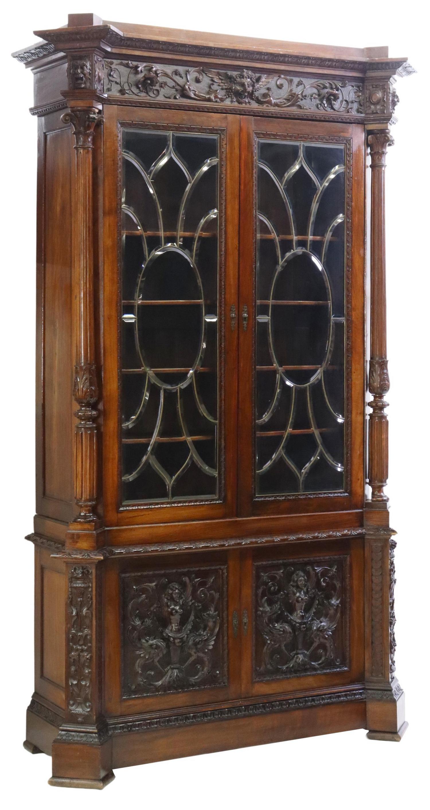 ITALIAN RENAISSANCE REVIVAL LEADED GLASS BOOKCASE: Italian Renaissance Revival carved bookcase, late 19th c., having molded cornice, frieze with scrolling foliates, grotesque masks, over leaded glass doors, flanked by fluted Corinthian columns, dual l