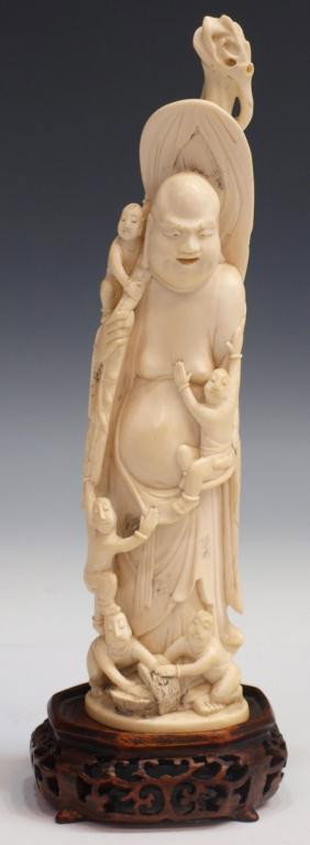 IVORY TUSK CARVING OF A BUDAI & CHILDREN: **This item will not be shipped Internationally** Ivory tusk carving of a Budai with children, remnants of dark stained accents, signed underfoot as pictured, on a pierced wood base, figure: 9.5"h, on