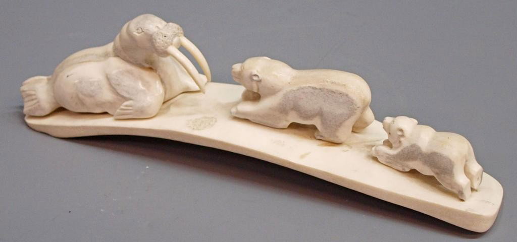 ALASKAN CARVED FOSSILIZED BONE, WALRUS & BEARS: Alaskan Native American carved fossilized bone formed as a walrus on an ice bridge confronted by two polar bears, 3"h, 11.5"w, 2.25"w Start Price: $100.00