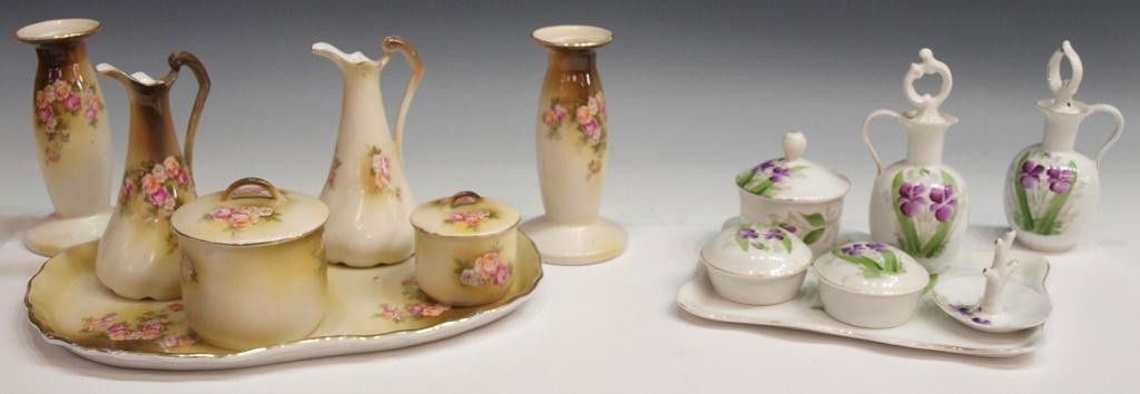 FLORAL DECORATED PORCELAIN DRESSER SETS: (lot) A group of two vintage porcelain dresser sets: an (7pc) set with transfer floral decoration; a (7pc) set in white painted purple flowers, stoppers with loss to cork; largest tray: 12.5"l, 8.25"w