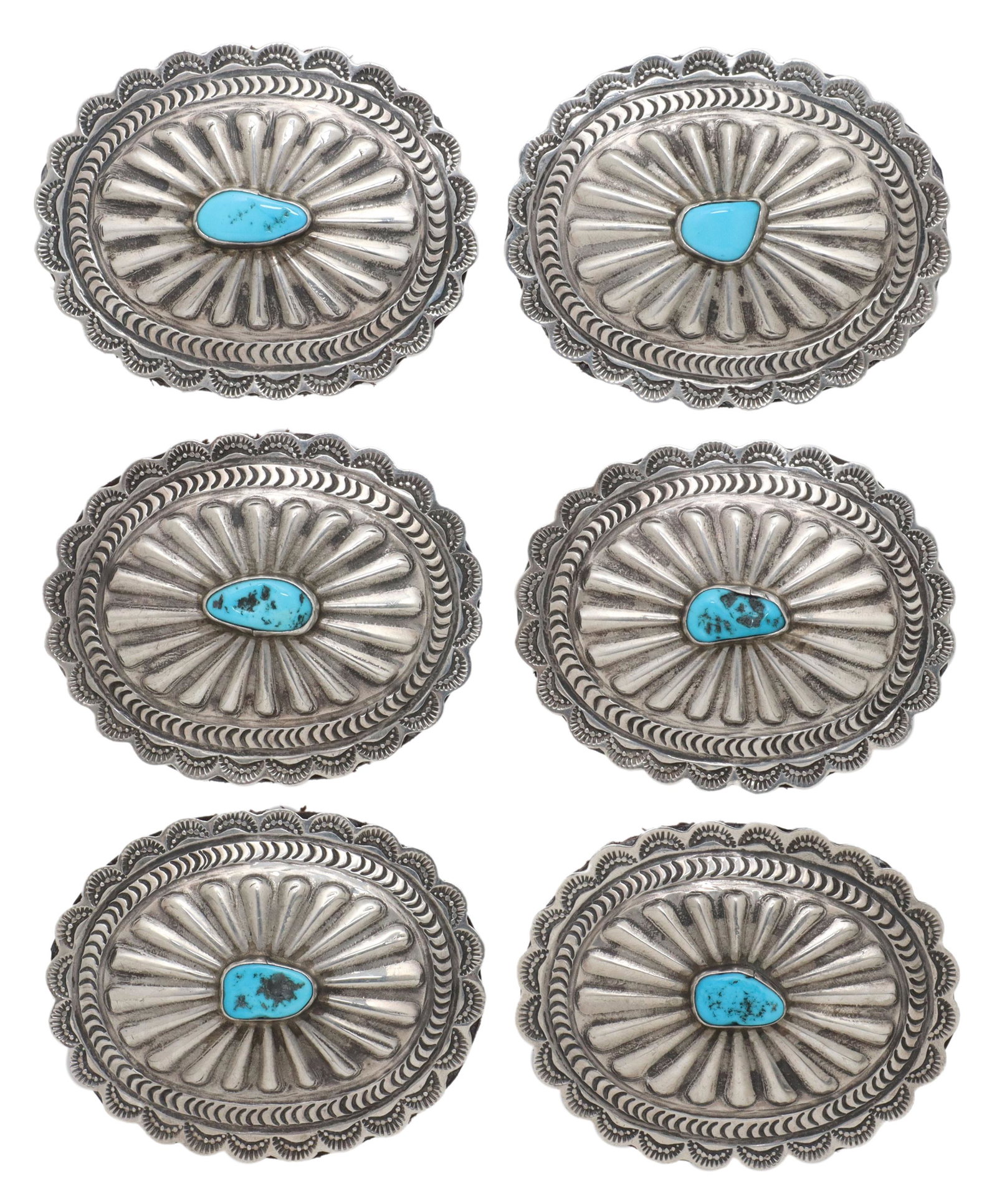 (6) NATIVE AMERICAN SILVER & TURQUOISE CONCHOS: (lot of 6) Native American silver (content unknown) conchos, oval form with scalloped edge, stamped designs, central bezel-set turquoise cabochon, leather backing, approx 2"h, 2.5"w; 175 grams total (