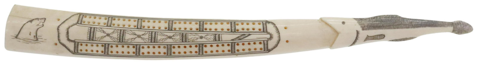 INUIT SCRIMSHAW WALRUS TUSK CRIBBAGE BOARD: Inuit walrus tusk carving, a cribbage board, scrimshaw decorated game area, with seals adorning each side, tapered end terminating in carved fish, worn stamp retaining partial maker's identification, 