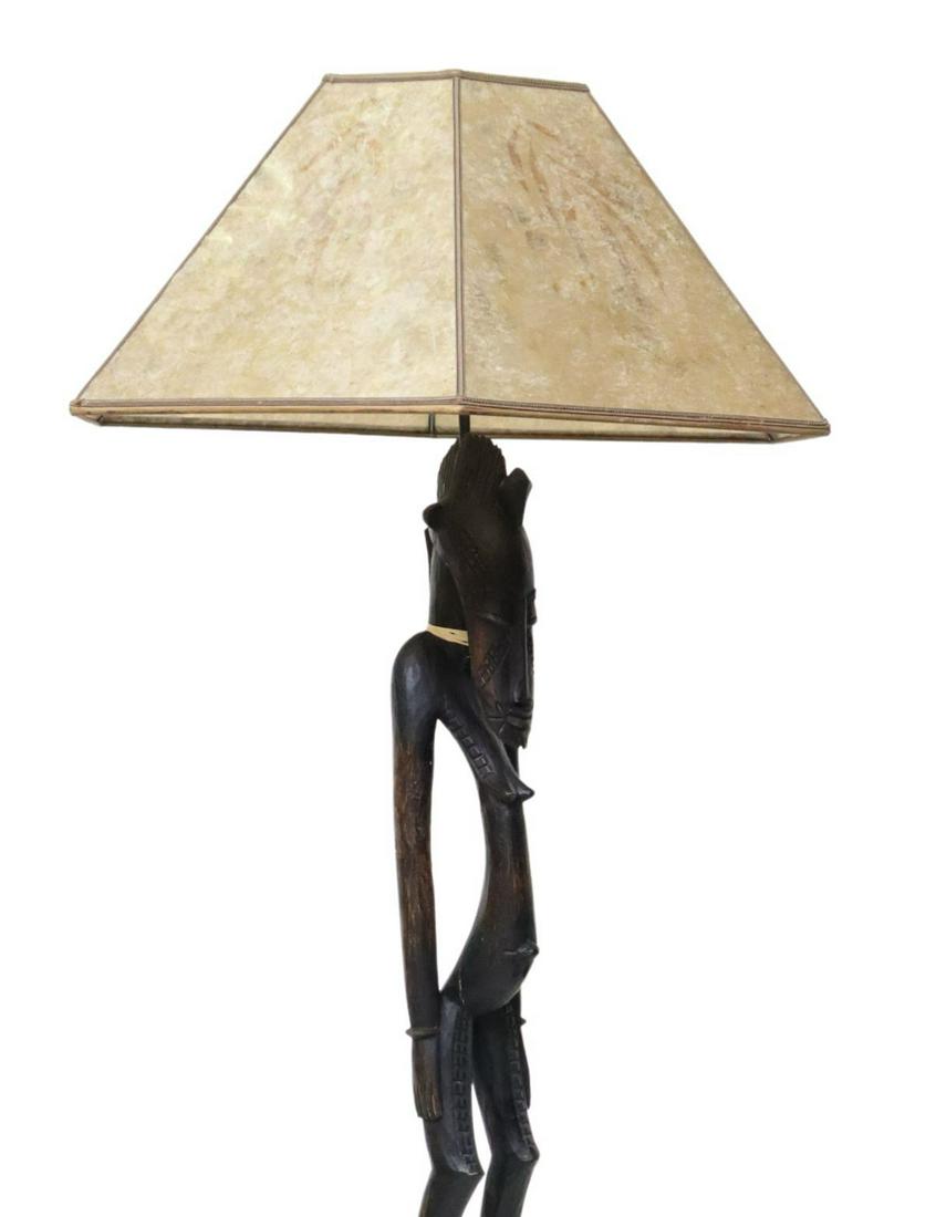 WEST AFRICAN CARVED FEMALE FIGURE FLOOR LAMP: West African carved wood standing figure, now mounted as a floor lamp, six-panel mica shade with natural foliage, concealing a single light, above female figure with coiffed hairstyle, elongated face,